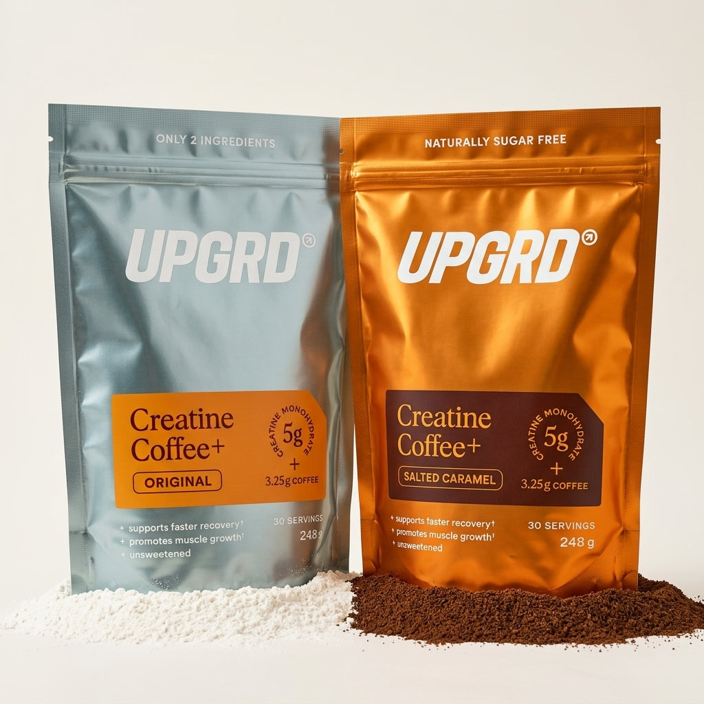 UPGRD Creatine Coffee+ Original and Salted Caramel pouches side by side, each standing in its own drift: white creatine powder under the Original and dark ground coffee under the Salted Caramel